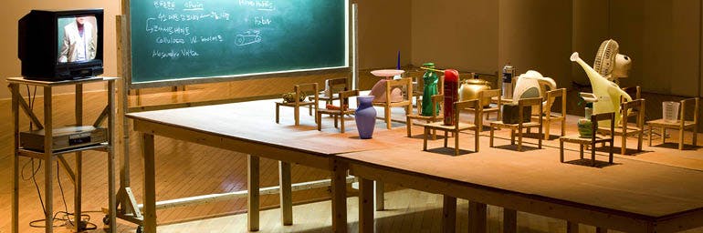 Objects Being Taught They Are Nothing But Tools, 2010. Kim Beom (Korean, b. 1963). Daily objects, wooden chairs, blackboard with fluorescent light, wooden tables, single channel video on TV monitor (21 min., 8 sec.); approx. 165.5 x 427.5 x 230 cm (overall). Courtesy of the artist. © Kim Beom. Photo by Park Myung-Rae